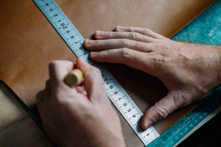 A man measures leather with a ruler.