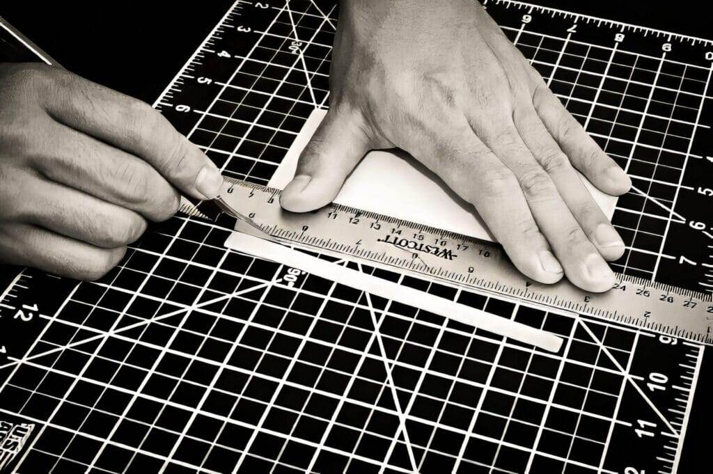 A person using a ruler to precisely cut a piece of paper.