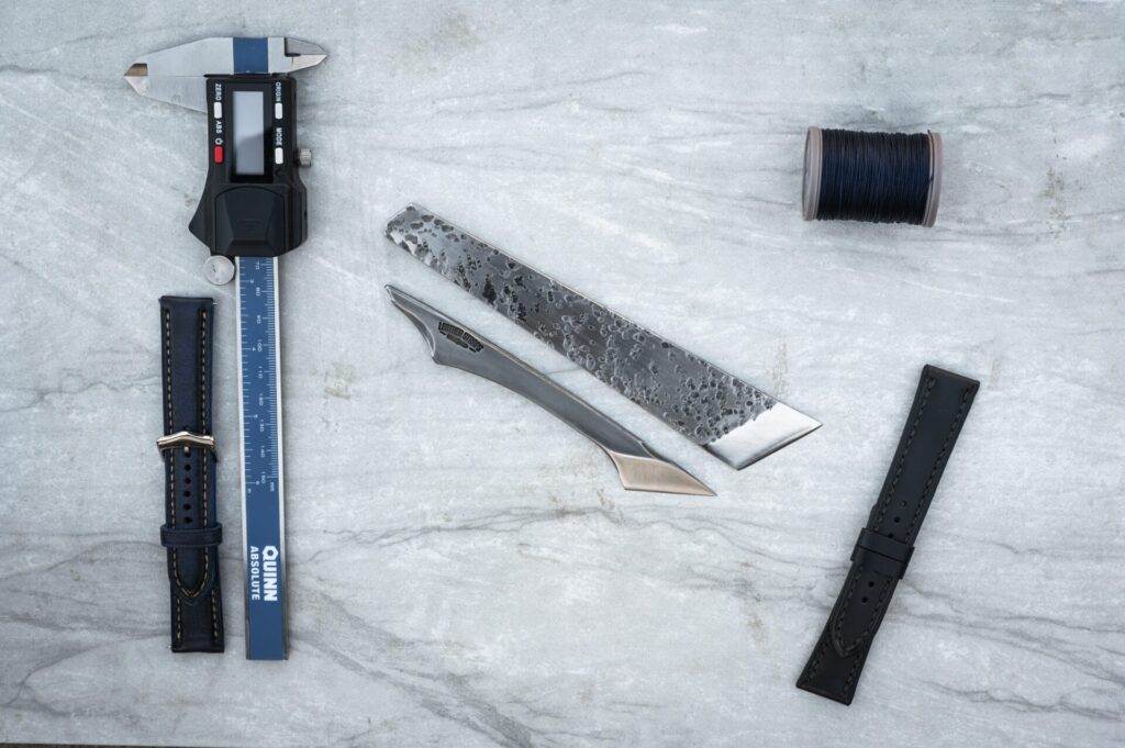 A knife and three rulers are arranged on a sleek marble table.