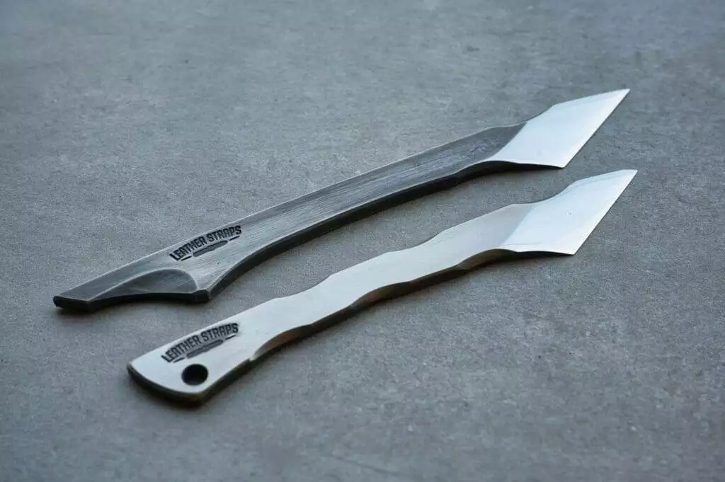 Two knives resting on concrete surface.