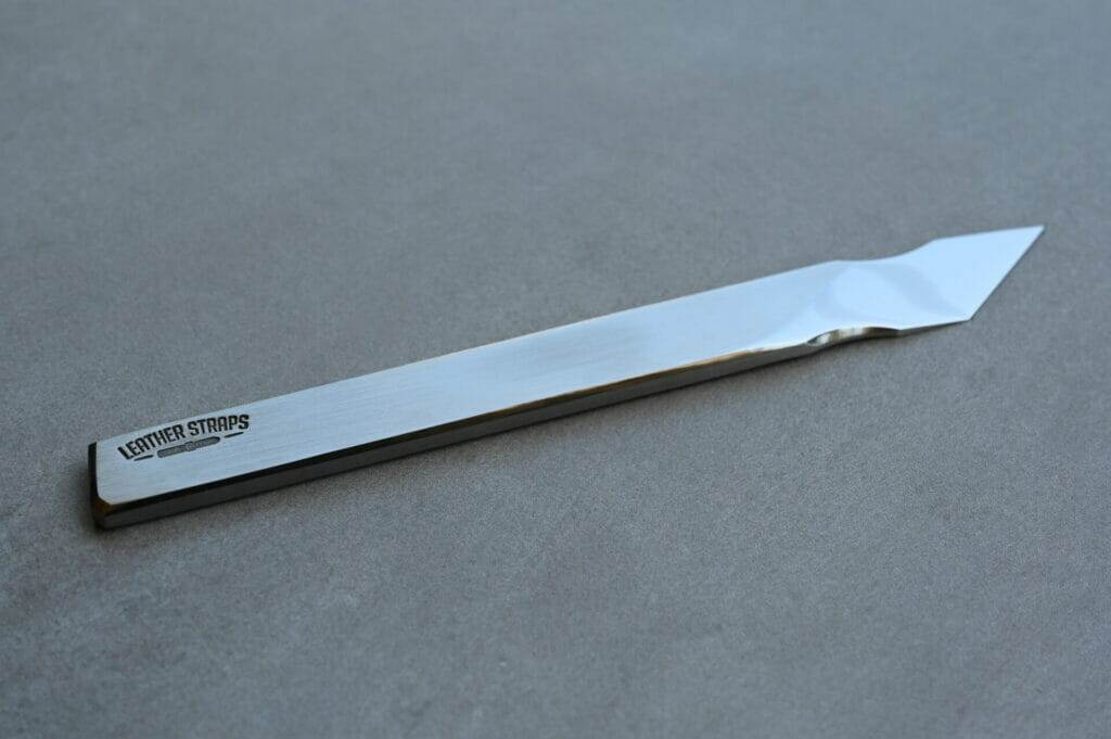 A stainless steel scalpel on a grey surface.