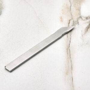 The Scribe Scalpel elegantly displayed on a smooth marble surface.