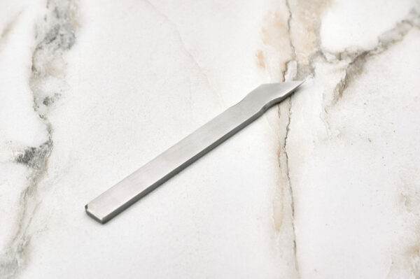 The Scribe Scalpel elegantly displayed on a smooth marble surface.