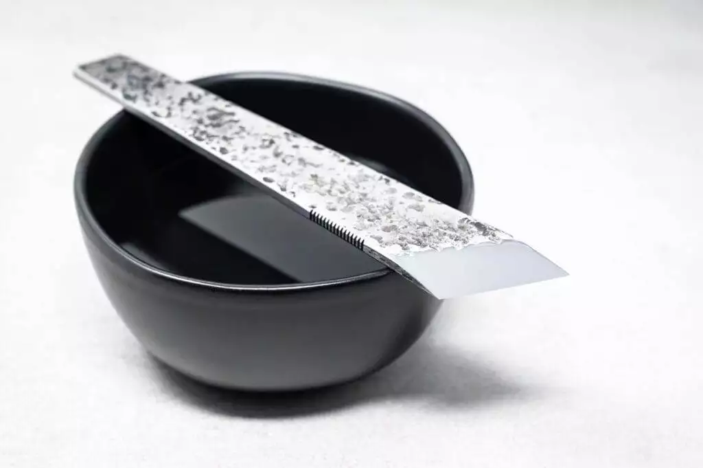 A black bowl with a silver spoon in it is placed on the table.