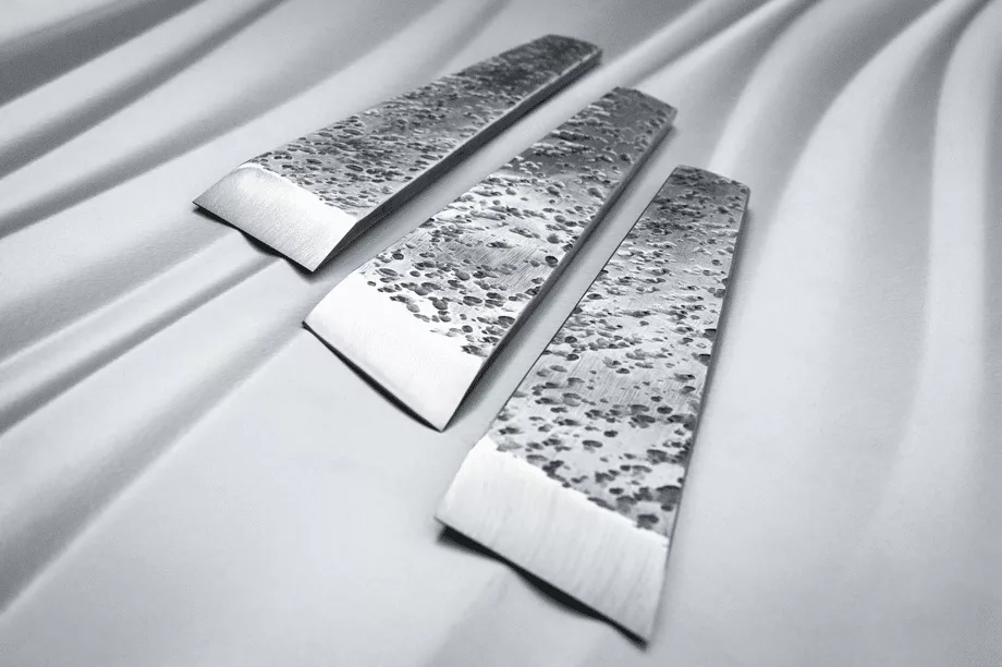 Three silver blades on a white cloth create a striking and elegant display.