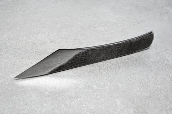 A black knife, part of the Halloween Special! - 3 Piece Full Set, laying on top of a concrete surface.