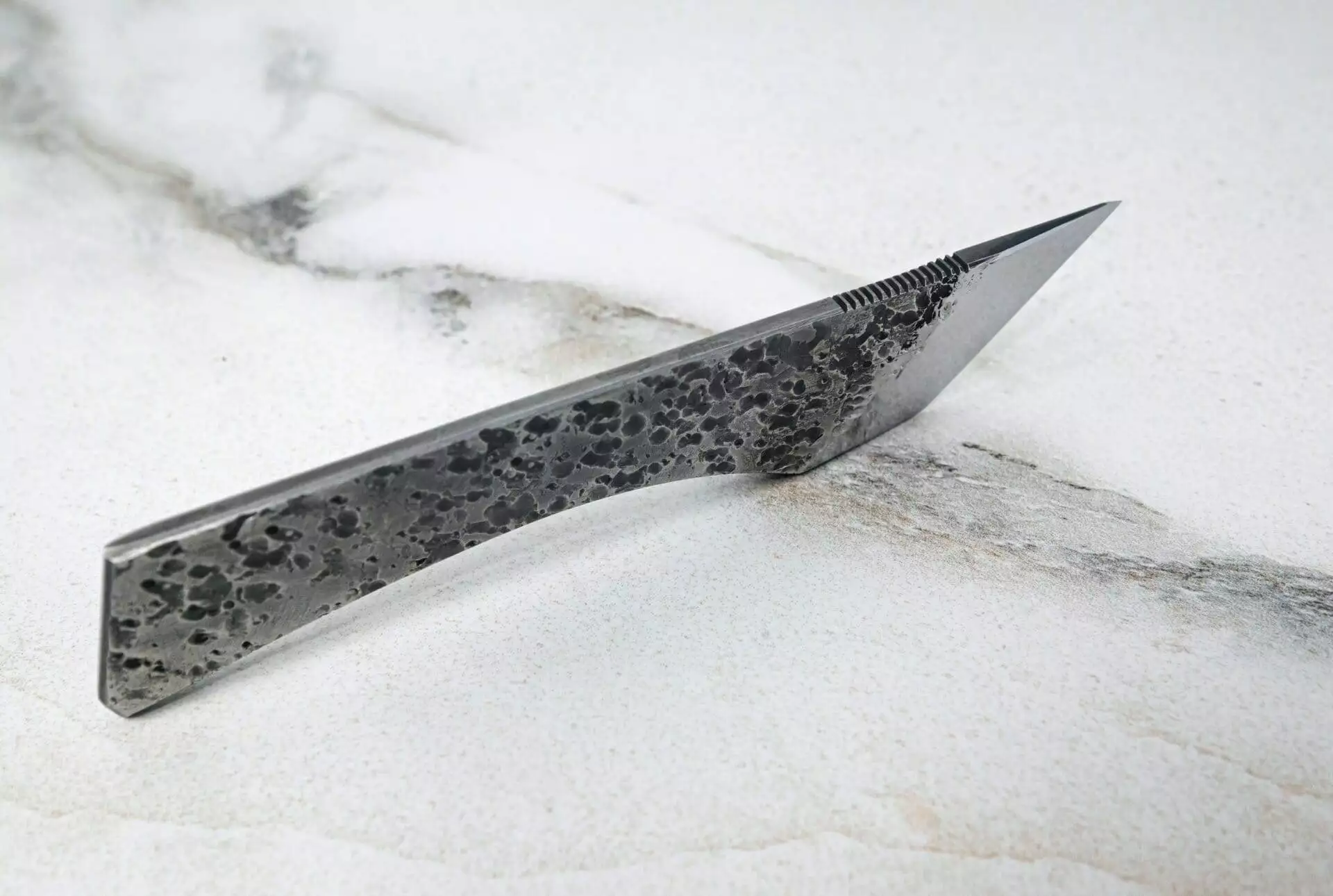 The Scorpion Skiver (45 Degree Bevel) with a black handle on a marble surface.