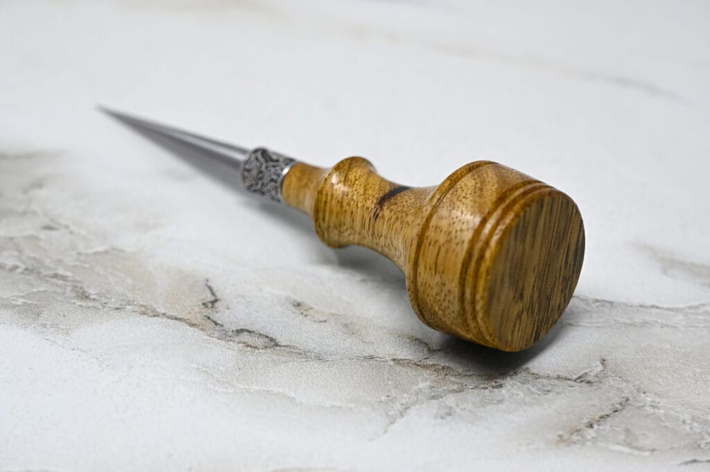 A wooden tool with a metal handle for 3 Leathercraft Knife Holiday Special on a marble surface.