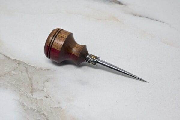 A small wooden tool on a marble surface, perfect for Christmas Special crafts requiring the 3 Piece Christmas Special - Small Awl, Essential Skiver and Riptide Scalpel.