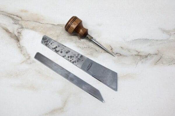 A pair of scissors and a knife, the 3 Piece Christmas Special - Small Awl, Essential Skiver and Riptide Scalpel, on a marble surface.