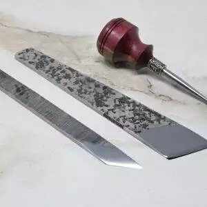 A pair of scissors and a knife, along with a 3 Piece Christmas Special - Small Awl, Essential Skiver and Riptide Scalpel, are displayed on a marble table.