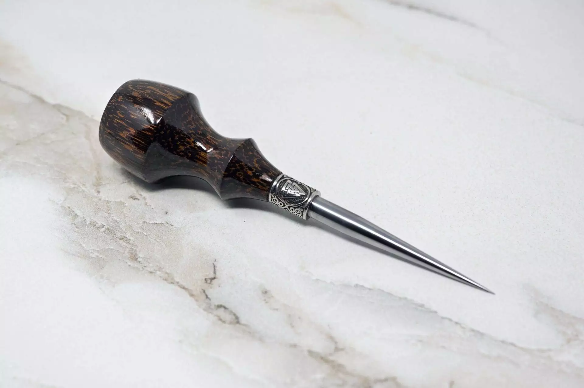 A 3 Piece Christmas Special - Small Awl, LE Essential Skiver and Riptide Scalpel with a black handle on a marble surface.