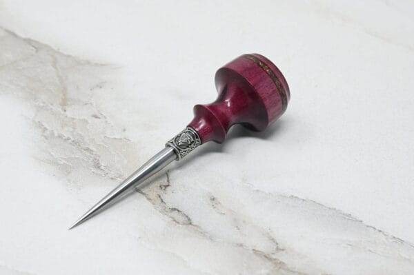 A small wooden tool with a metal tip, known as a Pre-release sale Japanese Leather Knife + Small Awl, sitting on a marble surface.