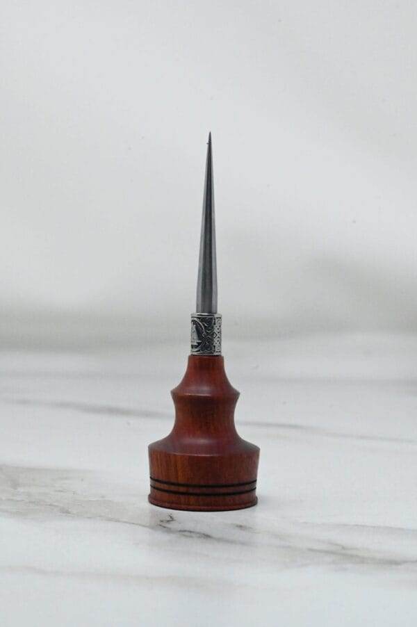 A small wooden Pre-release sale Japanese Leather Knife + Small Awl with a metal tip sitting on top of a marble table during the pre-release sale.