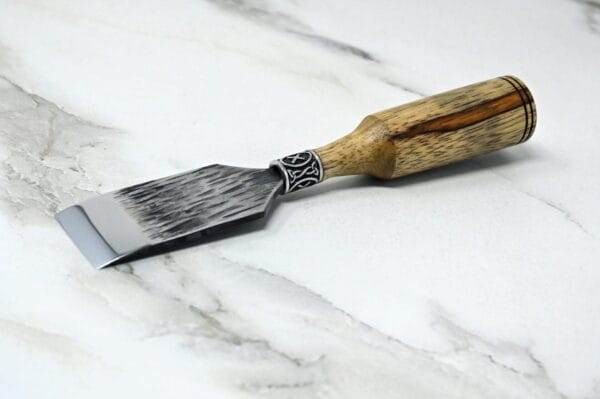 A Japanese Leather Knife with a wooden handle on a marble surface.