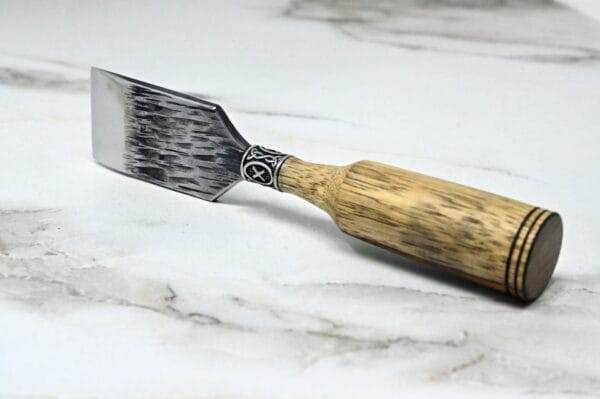 A Japanese leather knife with a wooden handle on a marble surface.