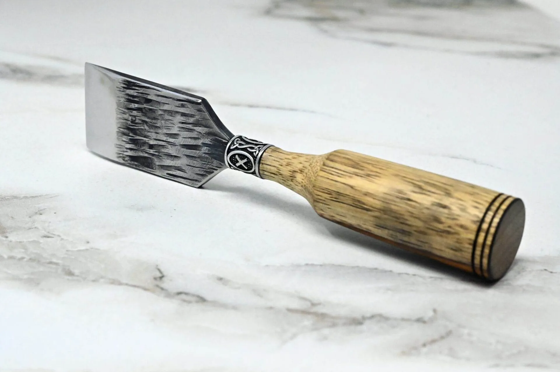 A Japanese leather knife with a wooden handle on a marble surface.