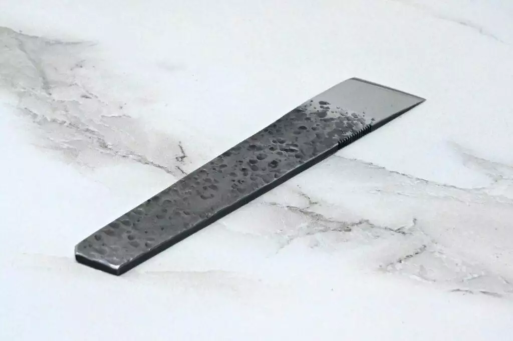 A black and silver hair comb on a marble surface with leather straps.