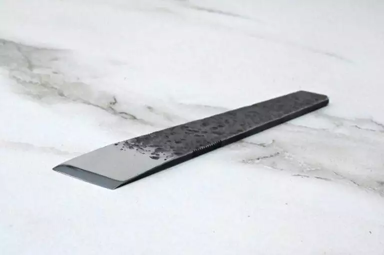 A knife with a black handle on a marble surface.