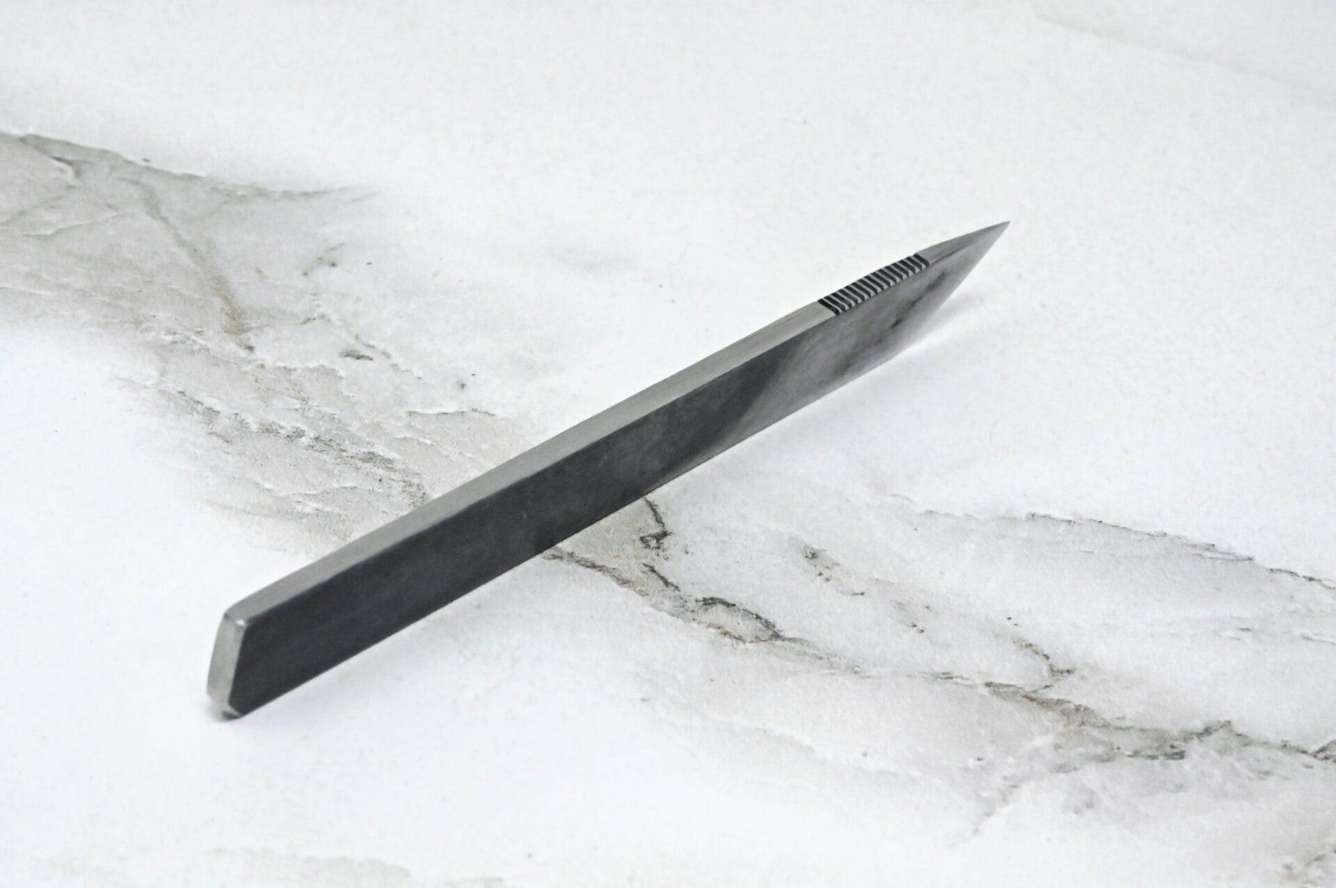 A black knife on a marble surface.