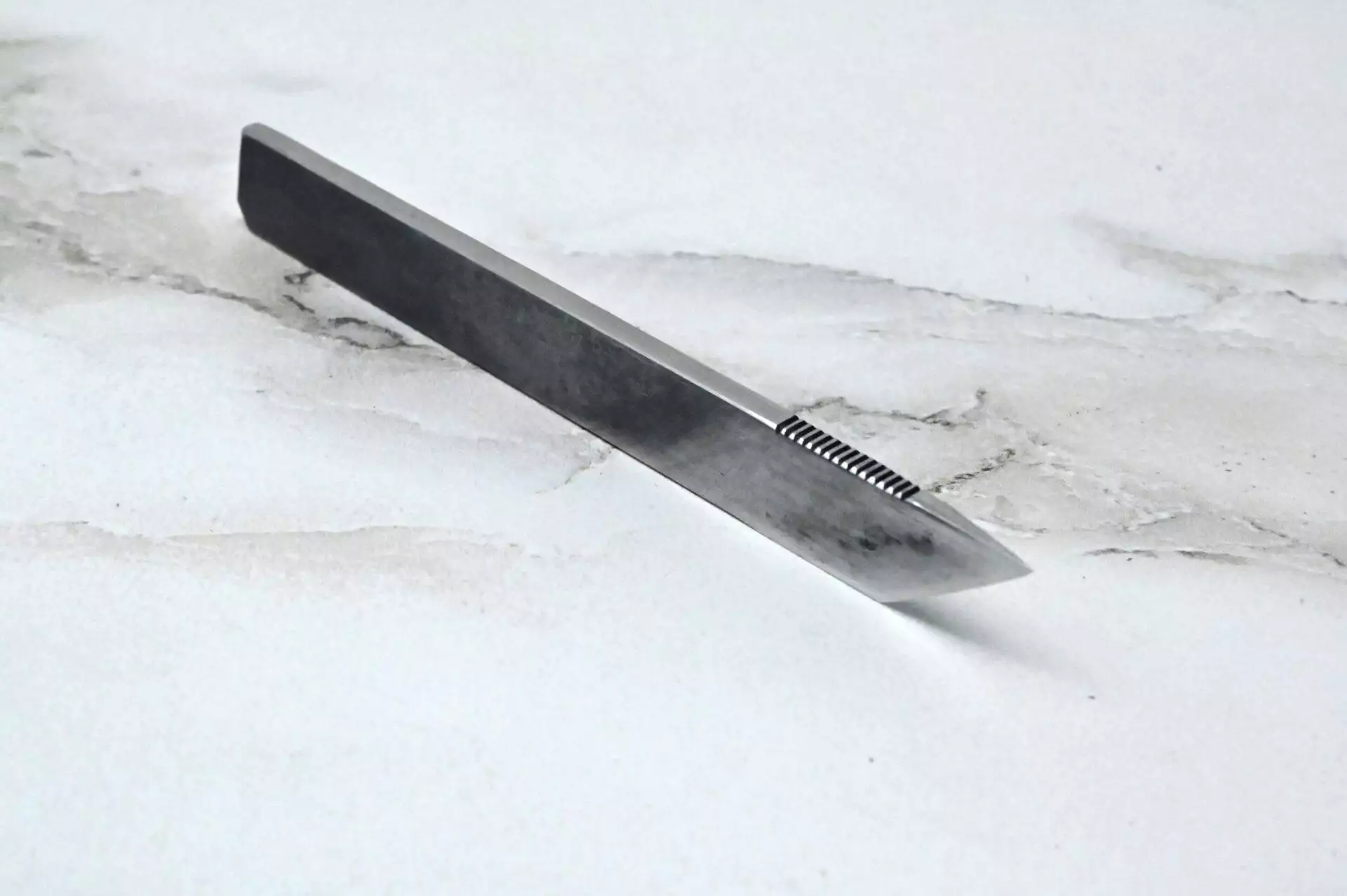 A metal knife on a marble surface.