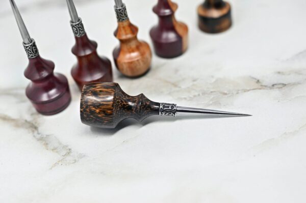 A collection of four Premium Handmade to Order Scratch and Poking Awls with wooden handles and metal tips arranged on a white marble surface.