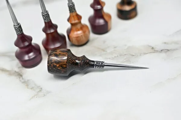 A collection of four Premium Handmade to Order Scratch and Poking Awls with wooden handles and metal tips arranged on a white marble surface.