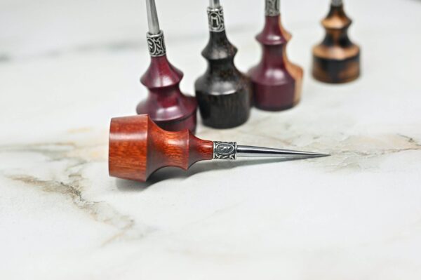 A set of Premium Handmade to Order Scratch and Poking Awls, featuring various shades of wood, positioned upright on a white marble surface, with one poking awl lying horizontally in the foreground.