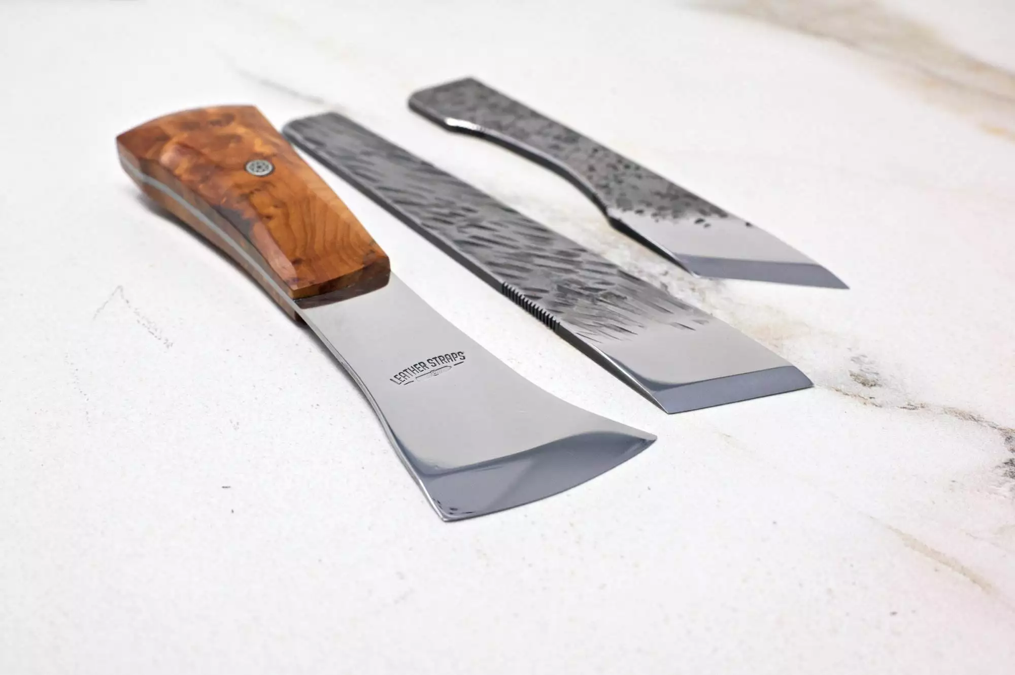 Displayed on a light surface, The Halloween 3 Piece Special showcases three knives with unique blade shapes and your choice of wood or metal handles, making it an elegant addition to your Halloween preparations.