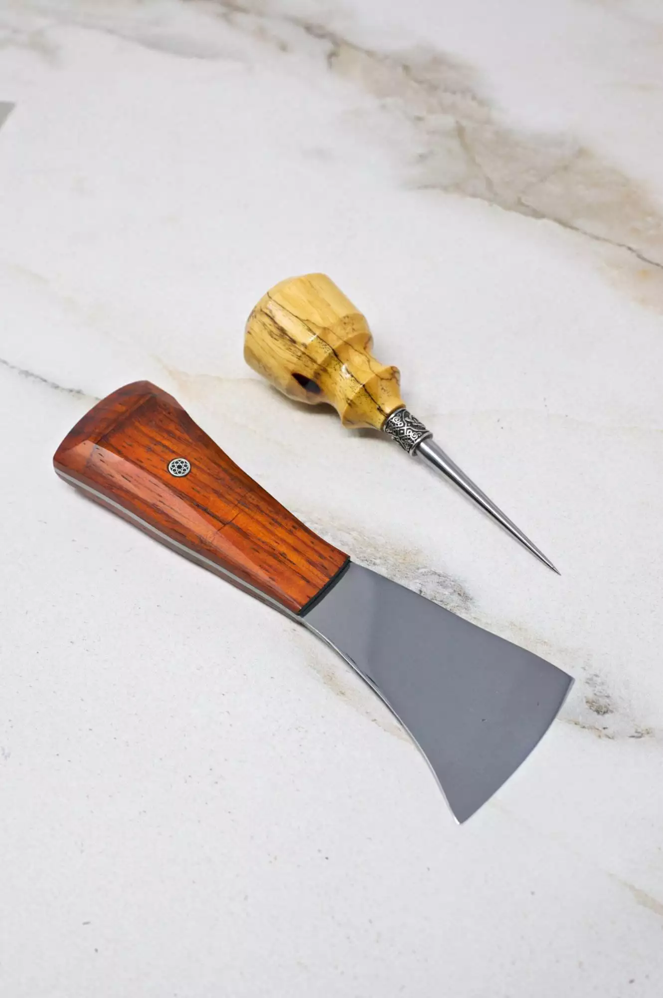 Introducing The Halloween 3 Piece Special, featuring a cheese knife with a wooden handle and a cheese awl, beautifully displayed on a marble surface. Ideal for your next Halloween gathering.