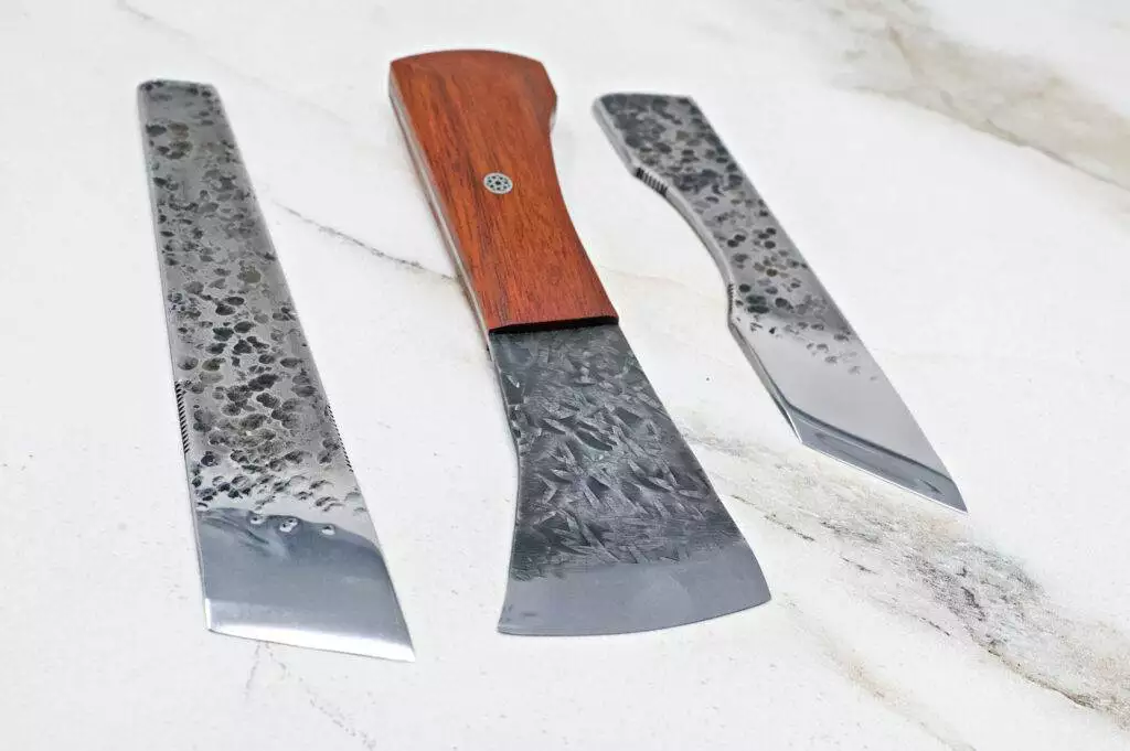 Three "Signature" American Leather Knives featuring textured metal blades and wooden handles are arranged on a marble surface.