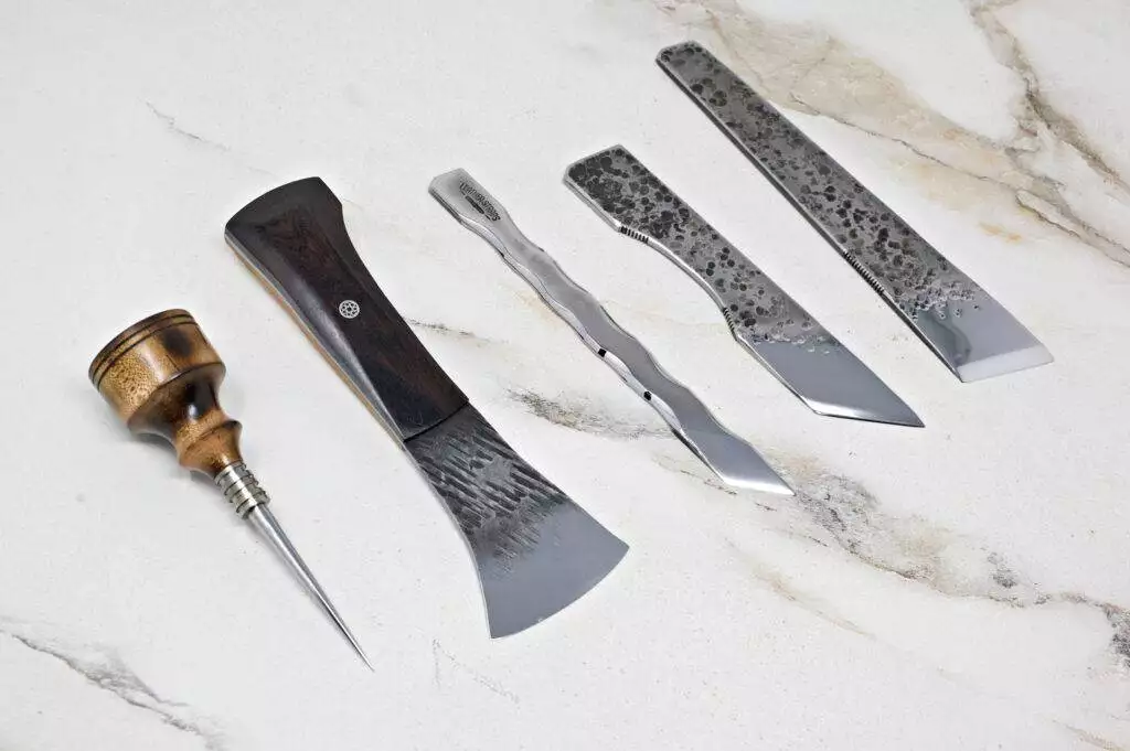 A selection of five "Signature" Leather Knives featuring diverse blade designs and handles is arranged on a marble surface.