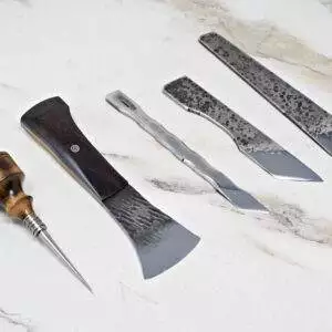 A set of five "Signature" Leather Knives, expertly crafted from metal and wood, displayed on a light marble surface.