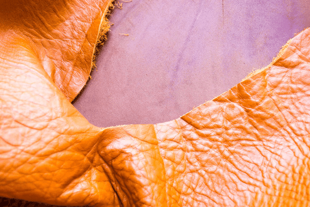 Close-up of textured full grain leather with frayed edges on a purple surface, showcasing the rich detail and quality of top grain craftsmanship.