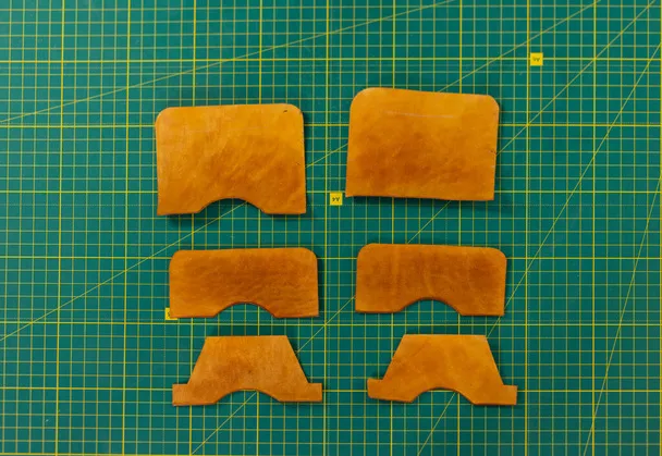 Six orange leather pieces, perfect for leathercraft projects, arranged in pairs on a green cutting mat with a grid pattern. Ideal working templates for precision and creativity.
.