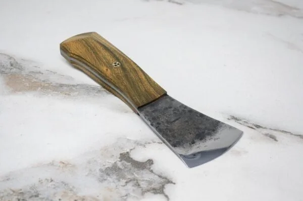 The Viper – American Signature Knife, featuring a sharp cleaver-style blade and a wooden handle, rests on a light marble surface.