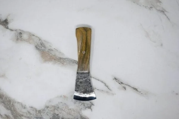 The Viper – American Signature Knife, featuring a compact wooden handle and a metal blade, rests on a marble surface.