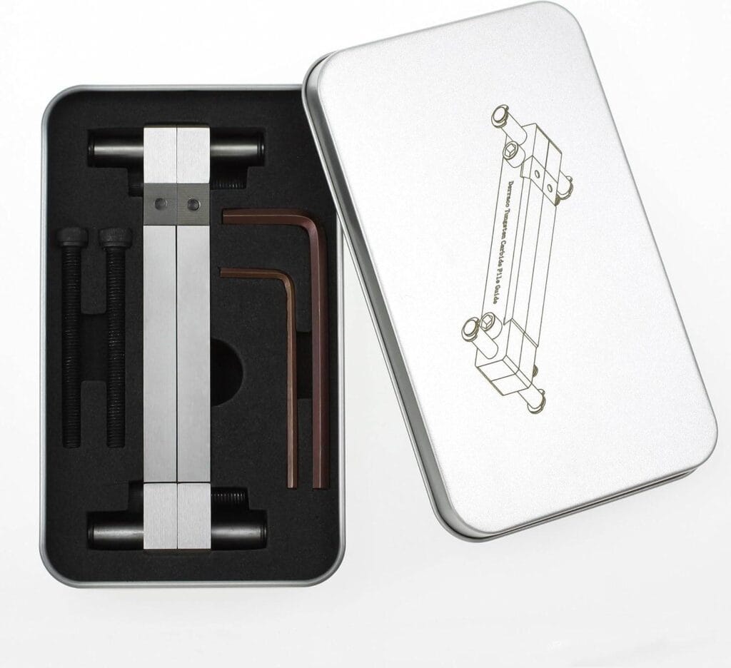 A metal tool kit featuring essential tools, including a rectangular component, two L-shaped wrenches, and bolts, nestled in a foam-lined tin box. The open lid showcases an illustration of the tools in use on top.